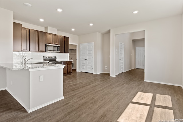 kitchen featuring light stone counters, dark hardwood / wood-style flooring, decorative backsplash, and stainless steel appliances