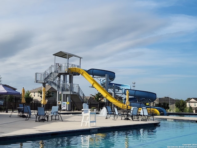 view of swimming pool featuring a playground, a patio, and a water slide