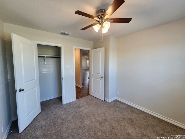 unfurnished bedroom featuring ceiling fan, a closet, and dark colored carpet