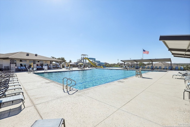 view of pool with a water slide and a patio area