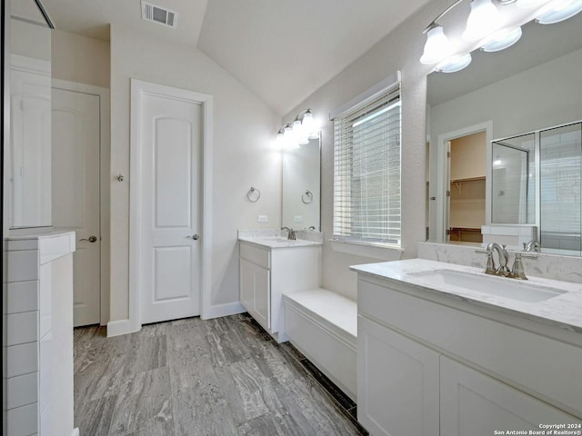 bathroom featuring wood-type flooring, vaulted ceiling, vanity, and an enclosed shower