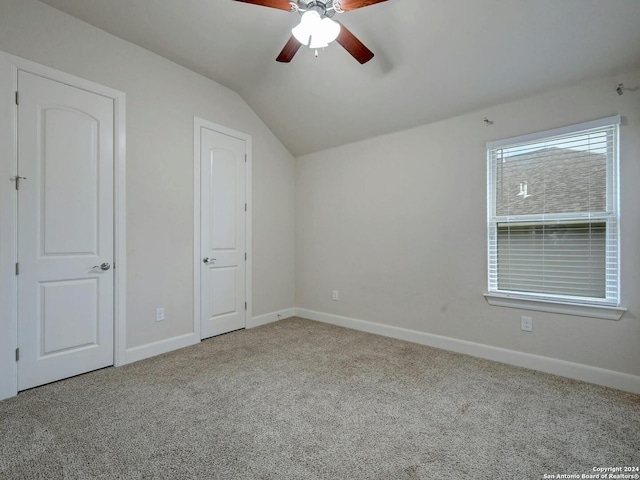 unfurnished bedroom featuring light carpet, vaulted ceiling, and ceiling fan