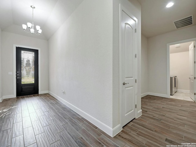 entrance foyer with a notable chandelier, lofted ceiling, and dark hardwood / wood-style floors