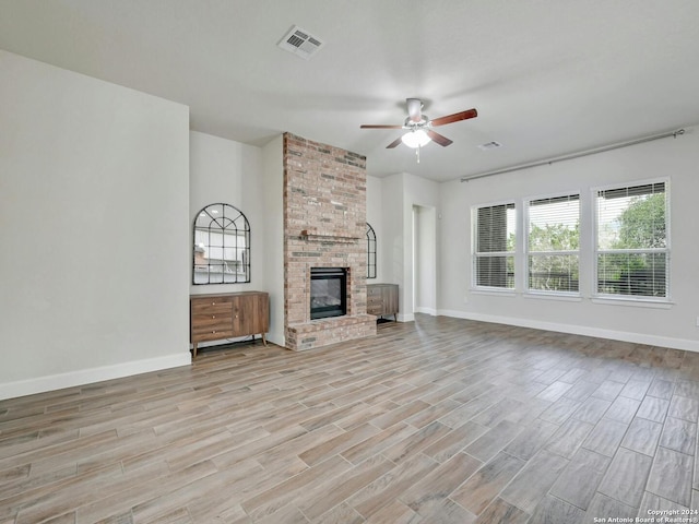 unfurnished living room with ceiling fan, light hardwood / wood-style flooring, and a brick fireplace