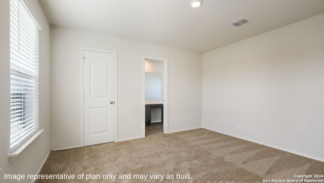 unfurnished bedroom featuring light carpet, a closet, and multiple windows