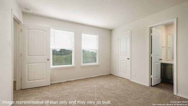 unfurnished bedroom featuring light carpet and connected bathroom