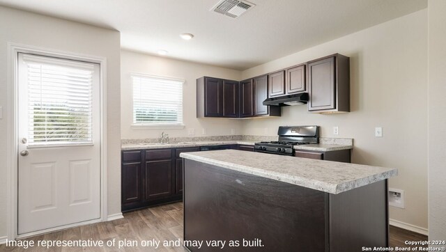 kitchen featuring dark brown cabinetry, sink, a kitchen island, light wood-type flooring, and gas stove