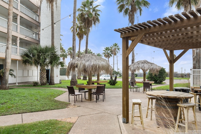 view of property's community featuring a bar, a pergola, and a yard