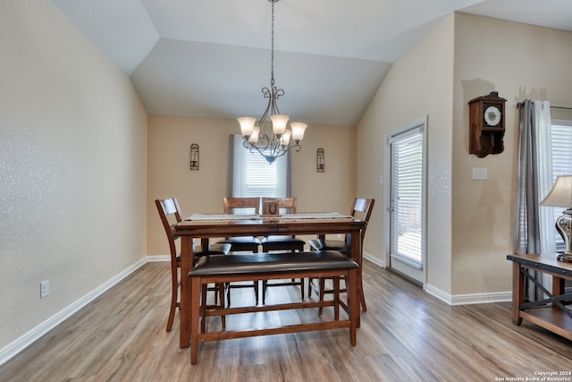 dining room featuring vaulted ceiling, a notable chandelier, plenty of natural light, and light hardwood / wood-style floors