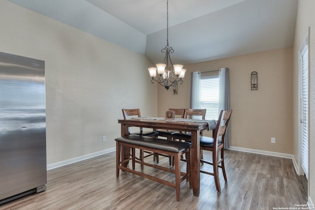 dining room with an inviting chandelier, lofted ceiling, and light hardwood / wood-style floors