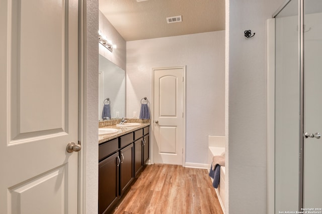 bathroom featuring vanity, a textured ceiling, a washtub, and hardwood / wood-style floors