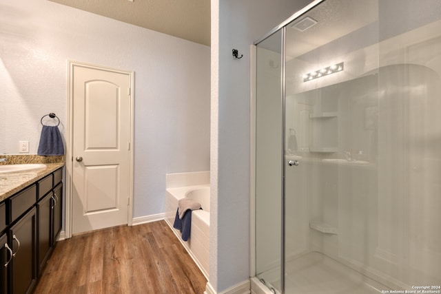 bathroom with independent shower and bath, hardwood / wood-style flooring, and vanity