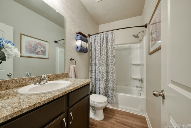 full bathroom featuring shower / bath combination with curtain, vanity, wood-type flooring, a textured ceiling, and toilet