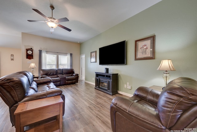 living room featuring ceiling fan, light hardwood / wood-style flooring, and a fireplace