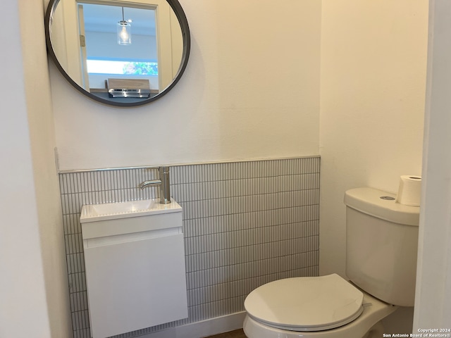 bathroom featuring tile walls, vanity, and toilet