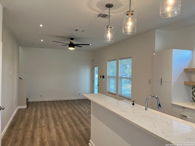 kitchen with light stone counters, ceiling fan, decorative light fixtures, dark hardwood / wood-style floors, and sink