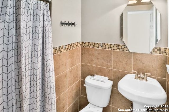 bathroom with tile walls, toilet, and a shower with shower curtain