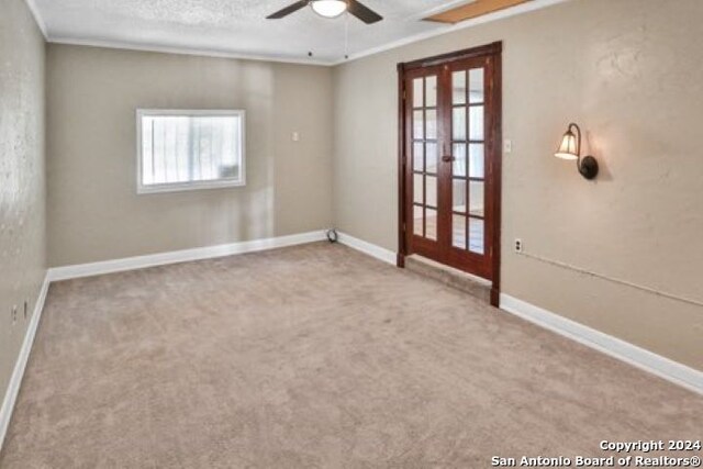 carpeted spare room featuring ceiling fan, a textured ceiling, crown molding, and french doors