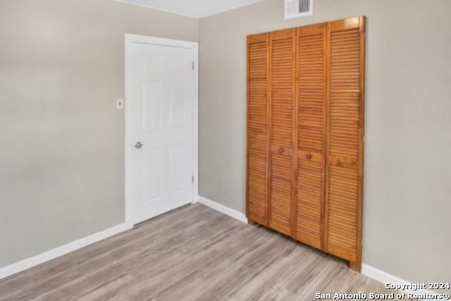 unfurnished bedroom featuring light hardwood / wood-style flooring and a closet