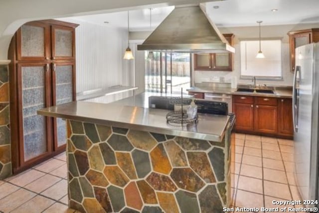 kitchen featuring pendant lighting, sink, wall chimney exhaust hood, stainless steel refrigerator, and a center island