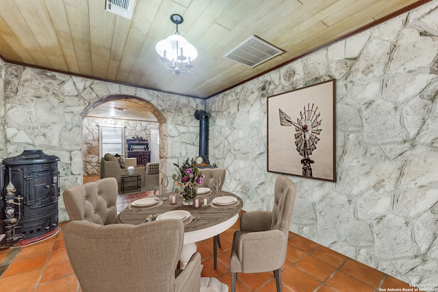 dining room with a wood stove, crown molding, and wood ceiling