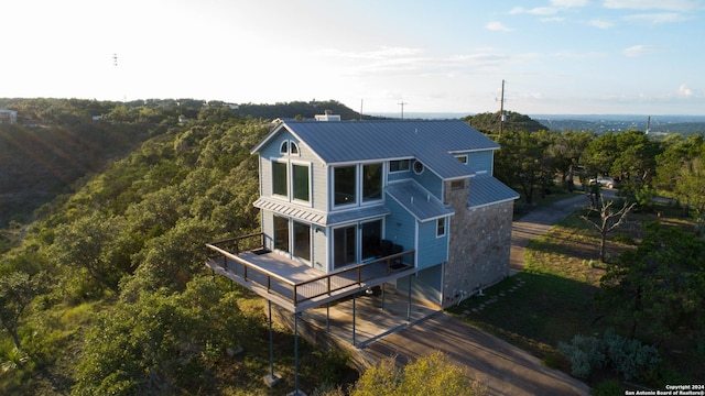461 Naked Indian, New Braunfels, TX 78132 - back of house with metal roof, a wooden deck, concrete driveway, and a forest view