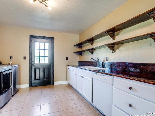 kitchen with washing machine and dryer, white cabinetry, dishwasher, light tile patterned floors, and sink