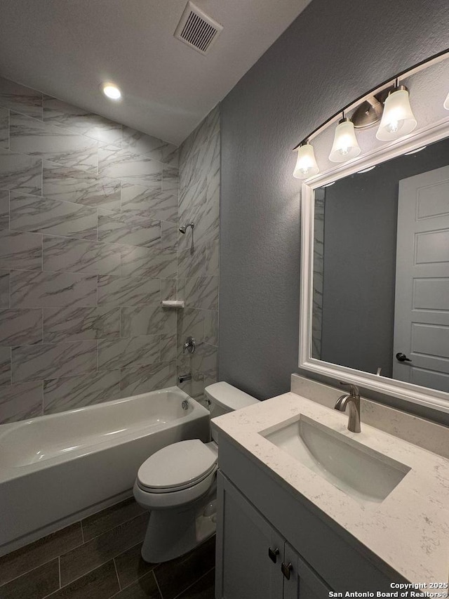 full bathroom with tiled shower / bath, vanity, and toilet