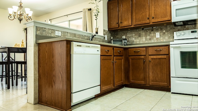 kitchen with an inviting chandelier, white appliances, decorative light fixtures, and backsplash