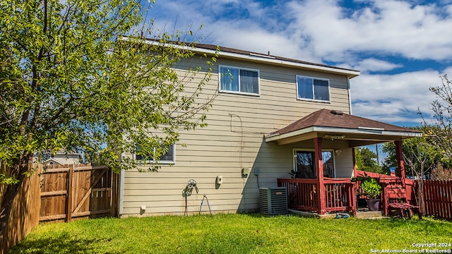 rear view of property with a lawn and central AC