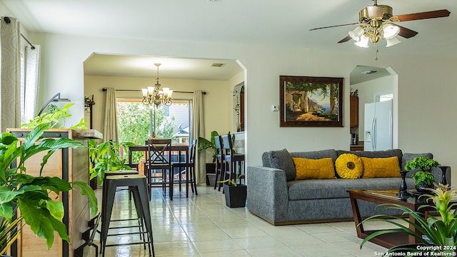 living room featuring light tile patterned flooring and ceiling fan with notable chandelier