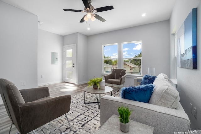 living room with electric panel, ceiling fan, and light hardwood / wood-style flooring