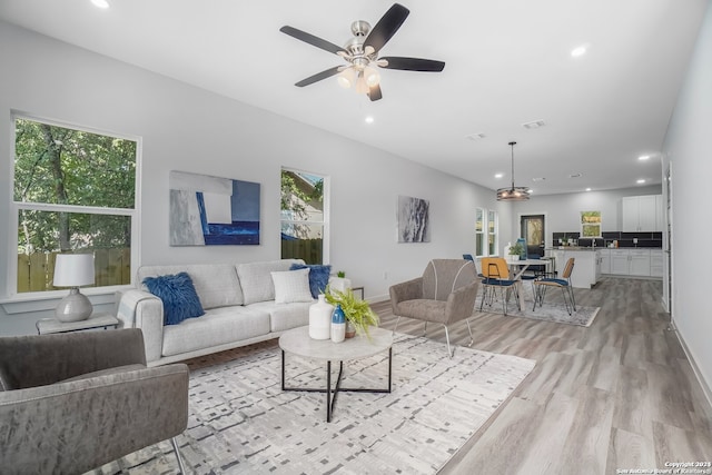 living room featuring light hardwood / wood-style floors, ceiling fan, and a wealth of natural light