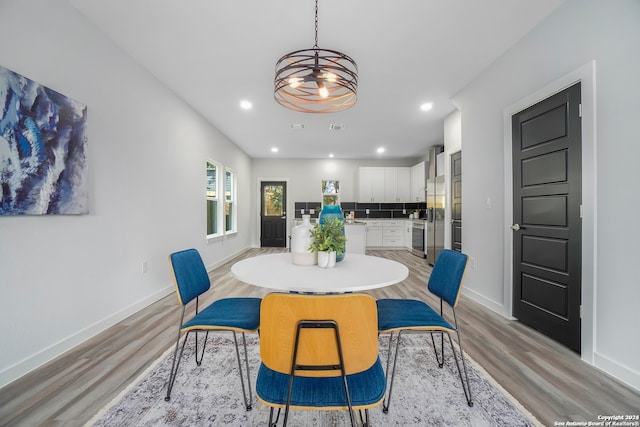 dining room with light wood-type flooring and a notable chandelier