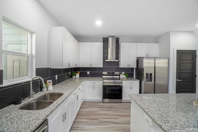 kitchen with light wood-type flooring, sink, white cabinetry, wall chimney exhaust hood, and stainless steel appliances