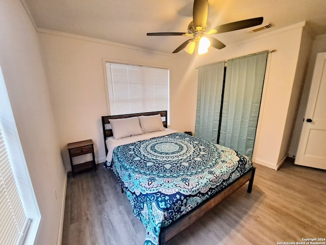 bedroom with wood-type flooring, ceiling fan, and crown molding