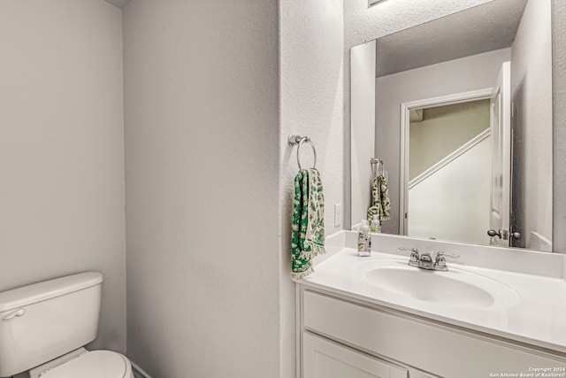 bathroom featuring a textured ceiling, vanity, and toilet