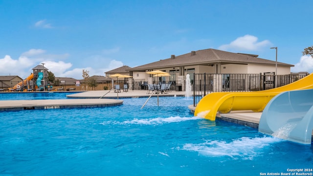 view of pool featuring a playground, a water slide, and a patio