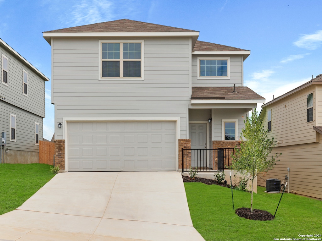 view of front of property with a front yard, central air condition unit, and a garage