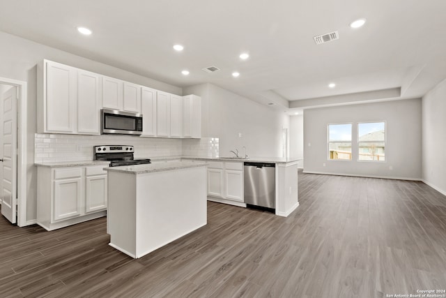 kitchen with white cabinets, appliances with stainless steel finishes, dark hardwood / wood-style flooring, and decorative backsplash