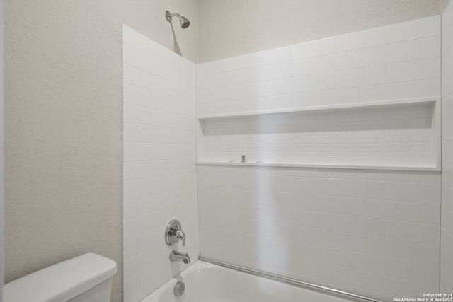 bathroom featuring tiled shower / bath and toilet