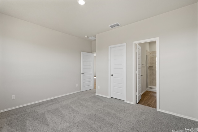 unfurnished bedroom with dark carpet, a closet, and ensuite bathroom