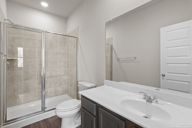 bathroom featuring wood-type flooring, vanity, toilet, and a shower with door