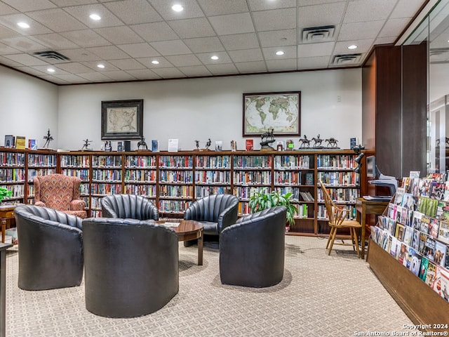 sitting room with a drop ceiling and carpet