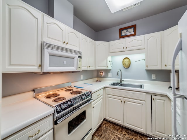 kitchen with white appliances, white cabinetry, and sink