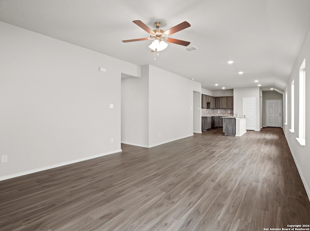 unfurnished living room featuring dark wood-type flooring and ceiling fan