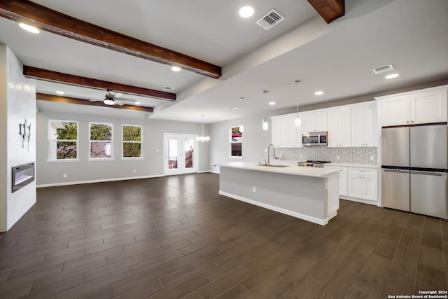 kitchen with appliances with stainless steel finishes, dark hardwood / wood-style flooring, white cabinetry, and a kitchen island with sink