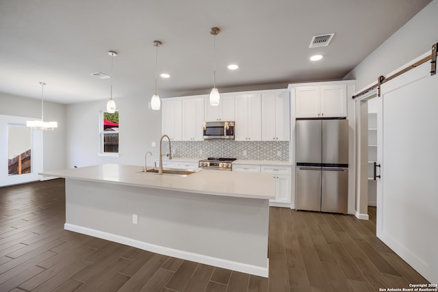 kitchen featuring a barn door, sink, stainless steel appliances, and an island with sink