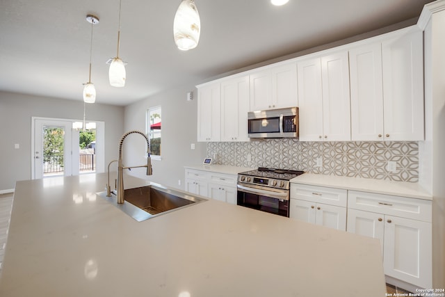 kitchen featuring sink, white cabinets, stainless steel appliances, and decorative light fixtures