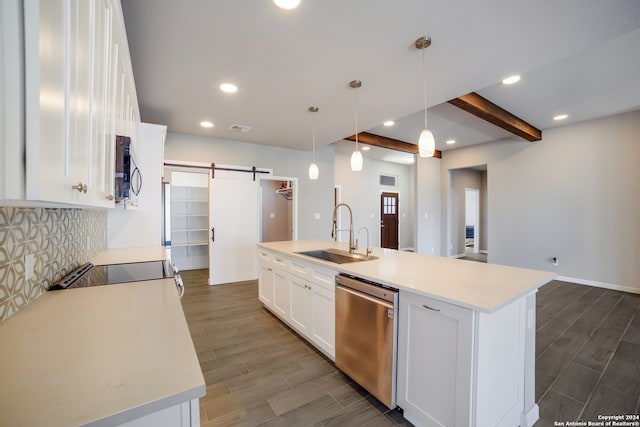 kitchen featuring stainless steel appliances, a kitchen island with sink, sink, a barn door, and white cabinets